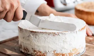 En hand sprider fluffig grädde på en tårta, en del av enkla tårtfyllningar.