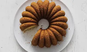 En gyllene sockerkaka med kardemumma, med en bit borttagen, ligger på en vit tallrik.