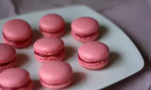 Rosa macarons med fyllning på en vit tallrik. Perfekt för ett macarons recept.