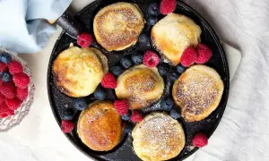 Små, gyllene pannkakor med pudersocker och bär, redo att avnjutas. Ett perfekt krabbelurer recept för frukost eller fika.