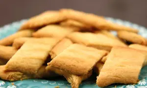 En hög med gyllene kolasnittar på en turkosblå tallrik. Perfekt för fikat, här är ett enkelt kolasnittar recept.