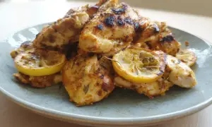 Grillad marinad kyckling med citronskivor på en ljusblå tallrik.