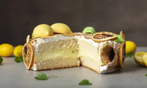 En skivad citron tarte med fluffig maräng, krämig fyllning och dekorerad med torkade citronskivor och gula marängkulor.