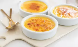 Tre krämiga crème brûlée i vita skålar med karamelliserat socker. Perfekt för ett enkelt creme brulee recept.