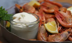 En skål med räkor och citronklyftor, med en liten burk krämig aioli. Perfekt för ett enkelt aioli recept.