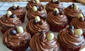 En bricka med chokladmuffins med krämig choklad frosting, dekorerade med små chokladägg i olika färger.