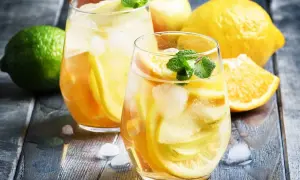 Två glas med uppfriskande vit sangria cava fyllda med frukt och is. Citroner, apelsiner och mynta ger en härlig sommarkänsla.