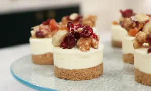Små mini cheesecakes med nötter och torkad frukt på en blåmönstrad tårtfat.