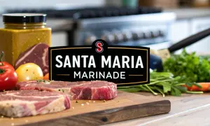 Råa ryggbiffar på en skärbräda med Santa Maria Marinade-logotypen, tomater, lök och färska örter.
