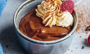 En krämig chokladpudding i en skål, toppad med vispad grädde, hallon och kanel. Perfekt för ett chokladpudding recept.