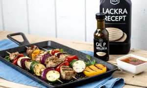 Grillspett med kött och grönsaker på en grillpanna, bredvid en flaska CAL P GRILLOLIA. Perfekt för ett läckert grillolja recept.