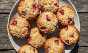 En tallrik med fluffiga muffins med jordgubbar, toppade med socker och citronskal. Perfekta för fika!