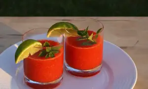 Två glas med fryst jordgubbsdaiquiri, garnerade med lime och mynta. Perfekt för ett somrigt strawberry daiquiri recept.
