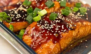 Saftig teriyaki lax med sesamfrön och färsk grön lök, redo att avnjutas.