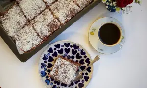 En saftig citronkaka i långpanna, toppad med kokosflingor, serveras med en kopp kaffe.