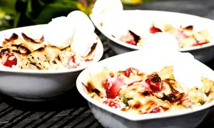 Tre skålar med jordgubbs-smulpaj toppad med vaniljglass. Ett perfekt Gino recept för en sommardessert.