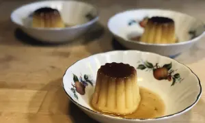 Tre krämiga creme caramel i vackra skålar med fruktmotiv. En härlig dessert som väntar.