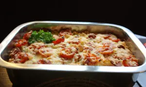 En gyllene makaronipudding med tomater och ost, redo att serveras. Ett perfekt recept för en mysig middag.