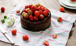 En kladdkaka med nutella, toppad med färska jordgubbar, ligger på en randig duk.