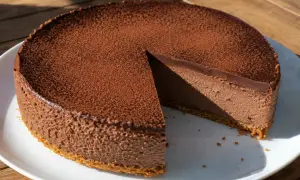 Chokladig oreo cheesecake med ett lager kakao på toppen, en bit är bortskuren.