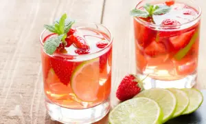 Två glas med uppfriskande alkoholfri bål fyllda med jordgubbar och lime, garnerade med mynta.
