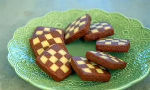 Schackrutor recept: Mörka och ljusa kakor i rutmönster på en grön, mönstrad tallrik. Perfekt för fikat!