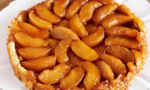 En gyllene tarte tatin med karamelliserade äppelklyftor som glänser. En klassisk fransk dessert som ser utsökt ut.