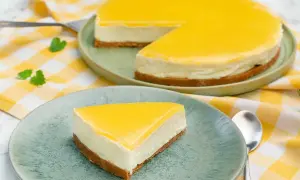 En krämig citron cheesecake med gul topping, en bit serverad på en tallrik.