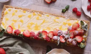 En avlång cheesecake med passionsfrukt, toppad med färska jordgubbar, hallon och mynta.