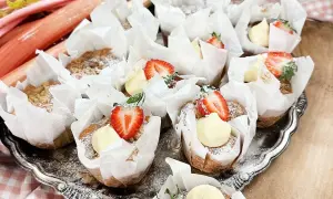 En bricka med rabarber muffins, toppade med grädde och jordgubbar. Perfekt för fikat!