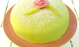 Grön prinsesstårta med rosa marsipanros och blad, pudrad med florsocker. Perfekt för ett prinsesstårta recept.