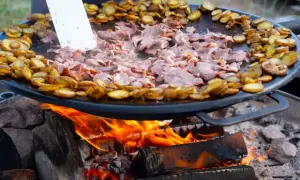 Kött och potatis steks på en Muurikka över öppen eld. Ett perfekt recept för utomhusmatlagning.