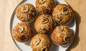 Sju gyllene bananmuffins med skivor av banan på toppen, redo att avnjutas. Ett perfekt bananmuffins recept för fika.