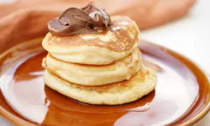 En stapel fluffiga amerikanska pannkakor med chokladkräm på toppen. Perfekt för ett amerikanskt pannkakor recept!