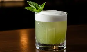 Grön, skummande drink med mynta och en kvist thai basil. En uppfriskande sommardrink.