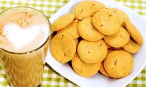 En kopp kaffe med hjärtformad lattekonst bredvid en hög med gyllene bondkakor. Perfekt för ett mysigt fika med detta bondkakor recept.