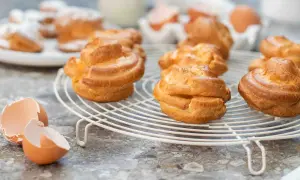 Nybakade petit choux på ett galler, med äggskal i förgrunden. Perfekt för en fika!