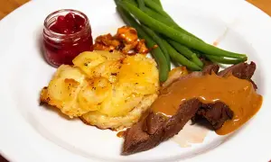Hjortstek i ugn med potatisgratäng, lingonsylt och gröna bönor. En klassisk svensk måltid.