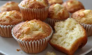 En tallrik med fluffiga vaniljmuffins, ett perfekt vaniljmuffins recept. En muffin är uppäten.