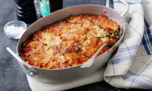 En ugnsform med en gyllene, bubblande melanzane alla parmigiana, toppad med riven ost och tomatsås. En klassisk italiensk rätt som doftar ljuvligt.