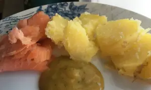En tallrik med gravad lax, kokt potatis och en klick gravlaxsås. Perfekt för ett snabbt och gott recept.