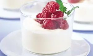 En len vit chokladmousse i glas, toppad med färska hallon och en myntakvist. En perfekt dessert för alla tillfällen.