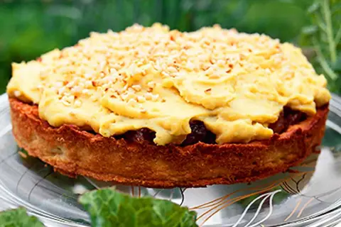 En härlig rabarberkompott tårta med gul kräm och nötter, serverad på ett fat utomhus.
