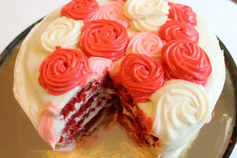 En skivad red velvet cake med fluffig frosting i rosformar.