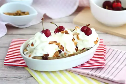 En läcker banana split med vispgrädde, körsbär och mandelflagor. En klassisk dessert som alltid går hem.