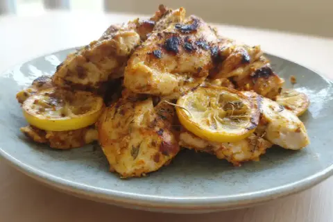 Grillad marinad kyckling med citronskivor på en ljusblå tallrik.