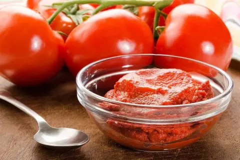 Färska tomater och en skål med tomatpuré, perfekt för ditt tomatpuré recept.