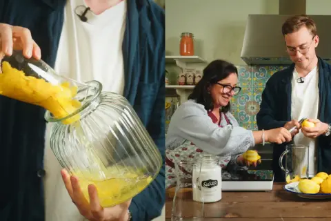 Två personer förbereder egen limoncello i ett kök. En häller citroner i en glasburk, medan den andra skalar citroner.