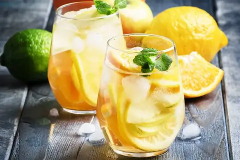 Två glas med uppfriskande vit sangria cava fyllda med frukt och is. Citroner, apelsiner och mynta ger en härlig sommarkänsla.