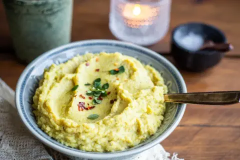 En skål med krämigt blomkålsmos, toppat med örter och chiliflakes. Perfekt som tillbehör till din middag, här är ett enkelt blomkålsmos recept.